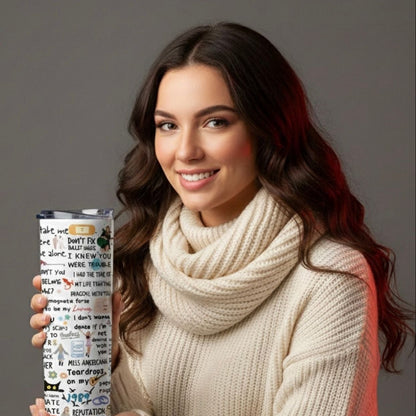 Woman holding a Taylor Swift tumbler with text and graphics, wearing a beige sweater and blue jeans on a gray background