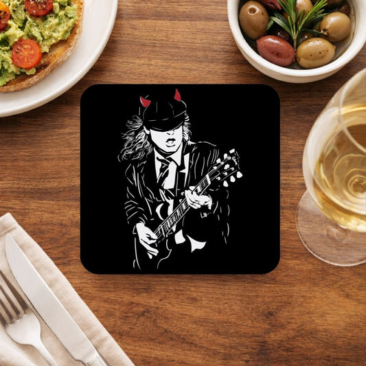 Coaster with a graphic of a musician playing guitar on a wooden table with food and drink. AC/DC Coaster The Banyan Tee