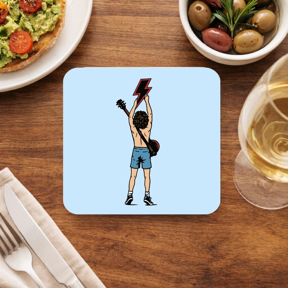 Coaster with a graphic design of a person holding a lightning bolt above their head on a wooden table with food and drink. AC/DC Coaster The Banyan Tee