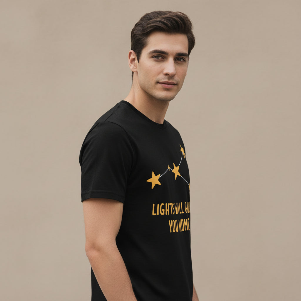 Black t-shirt with yellow star design and text 'LIGHTS WILL GUIDE YOU HOME' on a white background coldplay the bnayan tee 