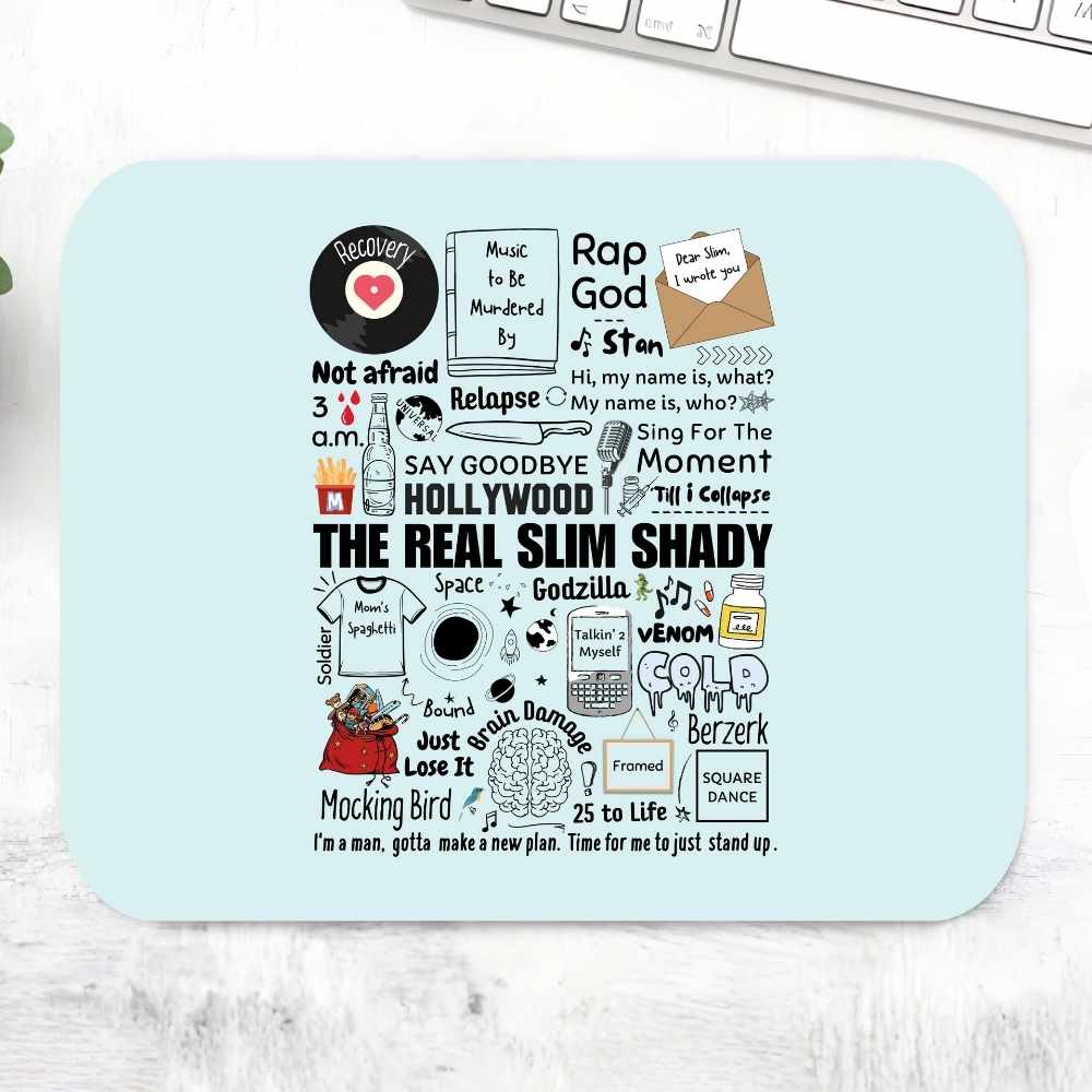 A rectangular light blue mouse pad with a black-and-white collage of slang, pop culture, and quote graphics, photographed on a white marble-like surface with part of a keyboard visible at the top. eminem shady doodle mousepad logitech large music band buy online united states of america usa the banyan tee tbt men women girls boys unisex
