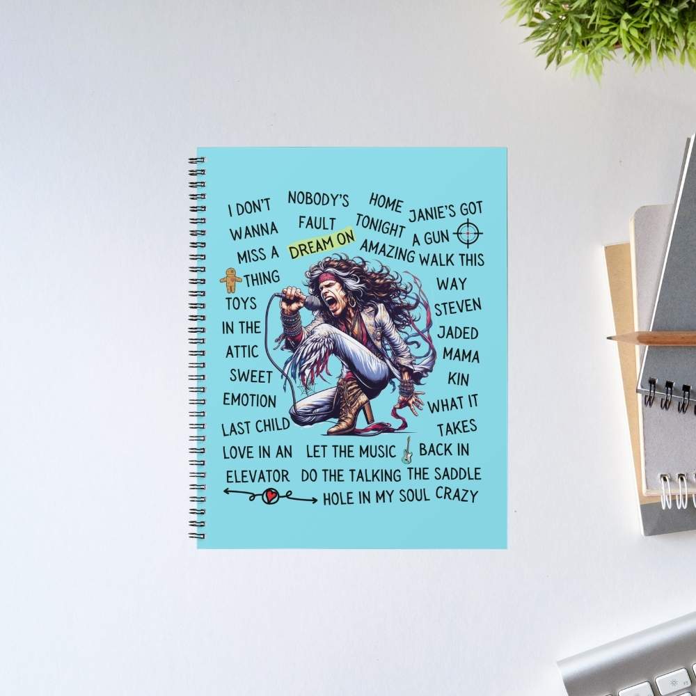 Notebook with lyrics on a light blue cover, placed on a white surface with a plant in the corner. aerosmith song story notebook notepad diary buy online united states of america usa the banyan tee tbt unruled