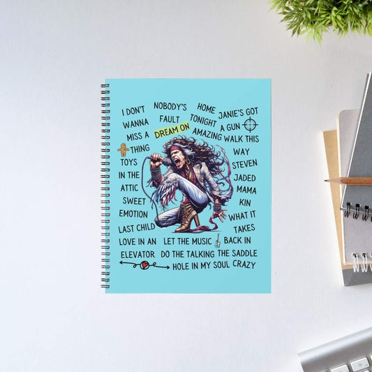 Notebook with lyrics on a light blue cover, placed on a white surface with a plant in the corner. aerosmith song story notebook notepad diary buy online united states of america usa the banyan tee tbt unruled