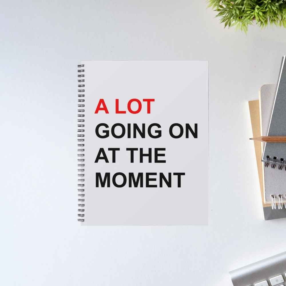 Taylor Swift A Lot Going On spiral notebook with bold red and black text 'A LOT going on at the moment' on a light grey cover – The Banyan Tee